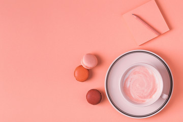 Cup of coffee with macaroons on pastel background.