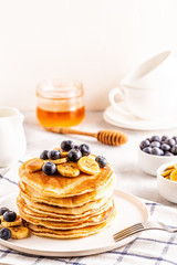 Pancakes with banana,  blueberries on white plate.