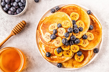 Pancakes with banana,  blueberries on white plate.