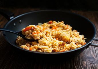 Traditional homemade Uzbek pilaf or plov in iron frying pan. Uzbek cuisine. Close Up. Selective Focus.