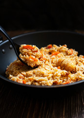Traditional homemade Uzbek pilaf or plov in iron frying pan. Uzbek cuisine. Close Up. Selective Focus.