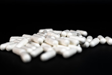 Medicine: bunch of white pills over black background