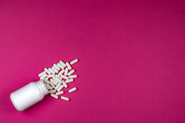 White pills spilling out of a toppled white bottle 