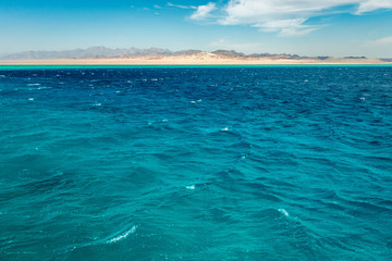 Seascape, view of the blue sea with high bald mountains in the background