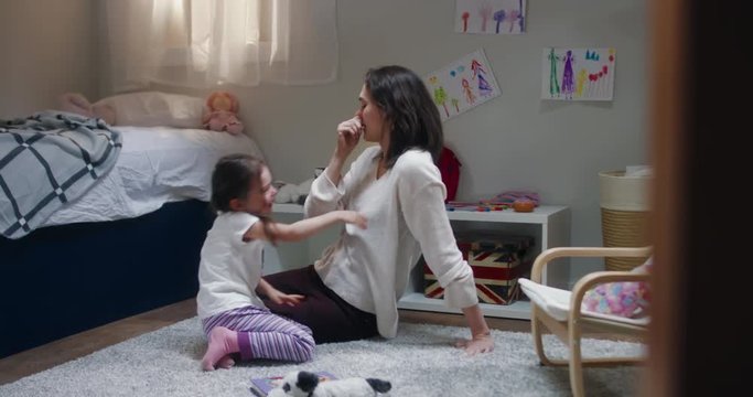 DOLLY Portrait of cute little girl playing together with her mother at home, evening shot, bedroom interior. 4K UHD RAW FOOTAGE
