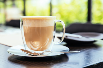 Front view of Hot Cappucino with blur green background. White froth on coffee and milk with copy space.