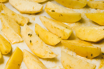 Delicious baked potatoes with rosemary on parchment, closeup. Vegetarian food. Potato country style