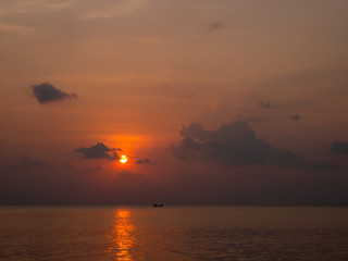 Silhouette of a boat on the background of the setting sun with clouds. Koh Phangan Thailand