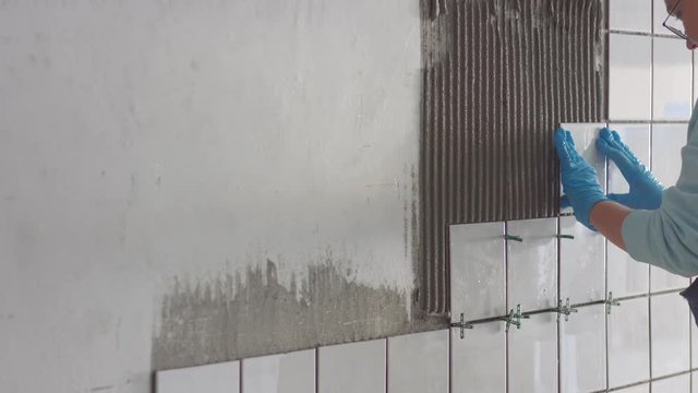 Ceramic tile aplication process. Tile application on the wall. Young female construct worker
