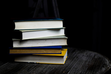 Stack of old books on round wood table with reading light during night