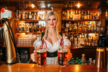 Waitress holds two mugs of beer at the counter
