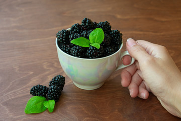 Cup full of blackberries on wooden background