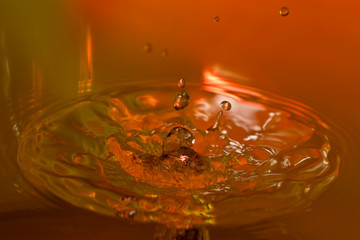 Tropfenfotografie - Nach dem Aufprall eines Wassertropfens bildet sich eine kleine Säule vor rotbraunem Hintergrund