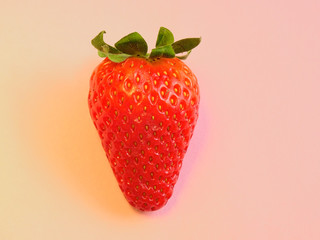 Isolated ripe red Strawberry, with its fresh Sepal like leaves, under a warm light on a pastel pink background