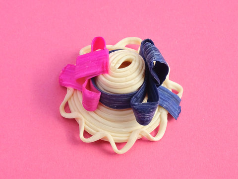 Close-up of a small handcrafted hat decorated with ribbons, made out the natural gum of the Manilkara chicle Tree, on a pink background
