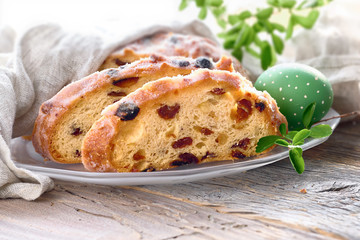 Easter bread, close-up on traditional fruty bread on rustic wood with fresh leaves and painted egg