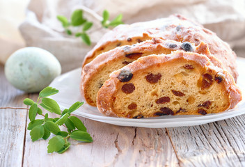 Easter bread, close-up on traditional fruty bread on rustic wood with fresh leaves and painted egg