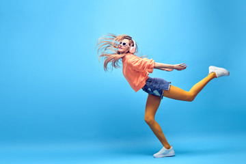 Obraz na płótnie Canvas Young easy-going happy hipster Woman dance Having Fun in Stylish fashion headphones. Beautiful excited Girl laughing enjoy music in summer Trendy outfit. Creative art dancing fashionable concept
