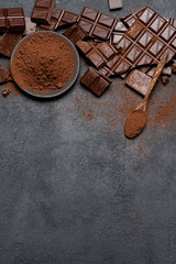 Frame or border made of Dark or milk organic chocolate pieces and cocoa powder on dark concrete backgound