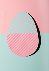 Papper easter egg one different on pink cross light blue pastel background.With dots and stripes. Minimal fashion concept .Flat lay . Top view.Copy space