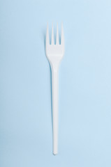 Plastic white disposable plug on a blue background. Concept plastic dishes, fast food, plastic pollution. Top view, flat lay.
