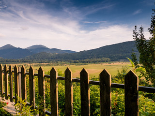 view of the green valley of the italian Matese mountains, wooden fence, cloudy sky