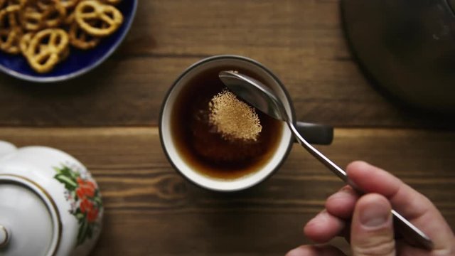 SLow motion shot of pour cane sugar from spoon into cup of tea