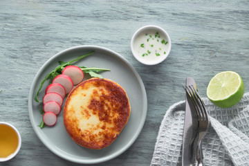 Fried round slice of cheese with green rucola salad with radish, yogurt sauce, olive oil and lime