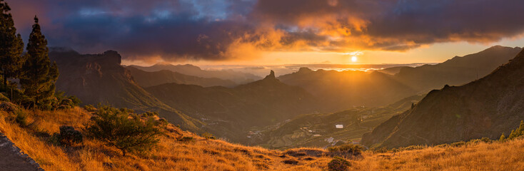 A panorama of a sunset over Gran Canaria, Spain. The Roque Nublo is visible on the left side....