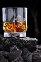 Glass of whiskey and ice.Creative photo glass of whiskey on stone .Copy space.Advertising shot