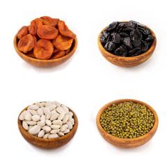Dried apricots, prunes, mung bean and white beans in wooden bowls on a white isolate.