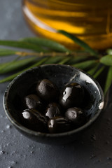 Black olives in round shaped black ceramic bowl.
