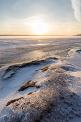 Serene landscape of ice, snow, icy rock and frozen and snowy lake in Finland in the winter at sunny morning.