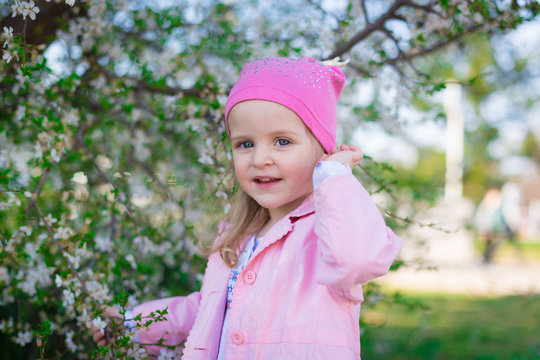  girl, pink hat and jacket, flowering trees, smile