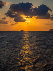 Silhouette of a ferry in the rays of the setting sun with clouds. Koh Phangan Thailand