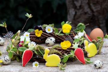 Ostergebäck und Weidenkranz mit Frühlingsblumen 