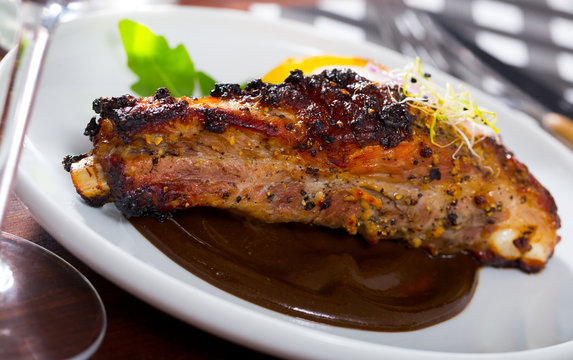 Зork ribs baked under mustard sauce served at plate with  spiced sauce