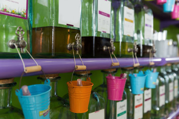 Image of colored pails hanging on taps of perfume bottles on shelves