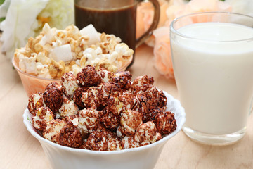 Cup of popcorn and a mug of milk on a wooden table close-up, tasty breakfast and a good start to the day
