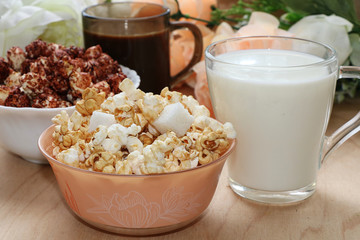 Cup of popcorn and a mug of milk on a wooden table close-up, tasty breakfast and a good start to the day