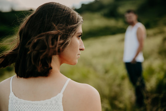 Frustrated young woman looking in distance, think about relationships, sitting separately with man