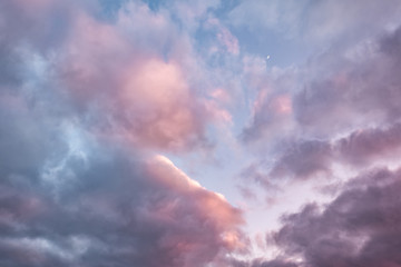 Blue sky background with evening fluffy curly rolling altocumulus altostratus clouds with setting sun. Good windy weather