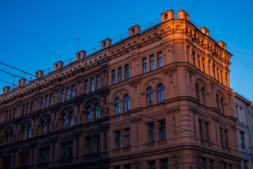 Obraz premium four-storey old renovated building under the rays of the setting sun