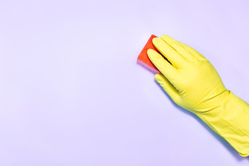 Man hand in glove with sponge on purple background.