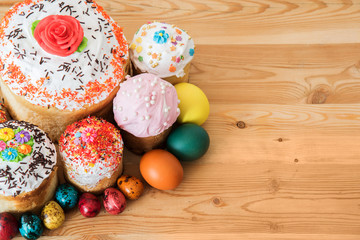 Orthodox Easter bread with raisins in white glaze and colored eggs on wooden table
