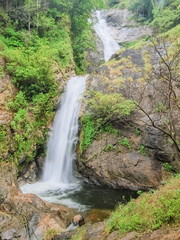 Fototapeta na wymiar Mae Pan Waterfall, view of silky water flowing from high cliff around with green forest background, Doi Inthanon, Chiang Mai, northern of Thailand.