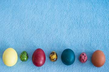 Easter colored eggs laid out in a line on a blue background