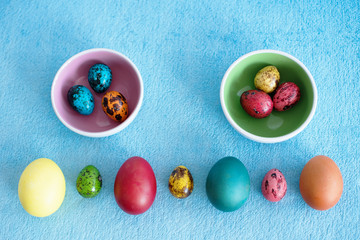 assorted colored Easter chicken and quail eggs on blue background
