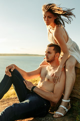 young couple sitting near lake having good time sunset