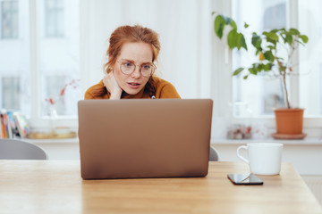 Serious worried young woman working on a laptop